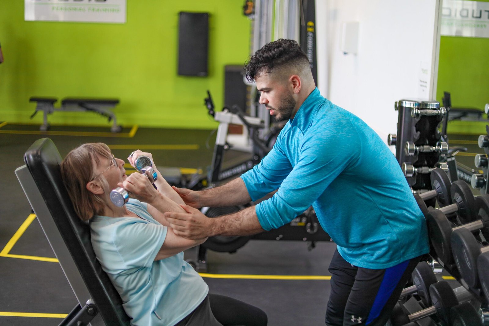 Personal trainer supporting a client during an adaptive training session